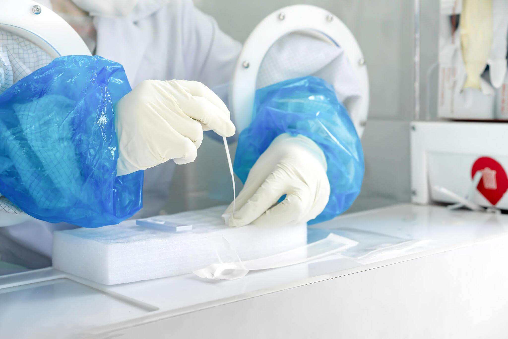 畫面近距離呈現(xiàn)了一名亞洲醫(yī)護(hù)人員在負(fù)壓室內(nèi)進(jìn)行新冠病毒（COVID-19）檢測時所佩戴的橡膠手套。這種特殊的工作環(huán)境對于有效防控病毒傳播、確保醫(yī)護(hù)人員乃至社區(qū)整體的安全至關(guān)重要。