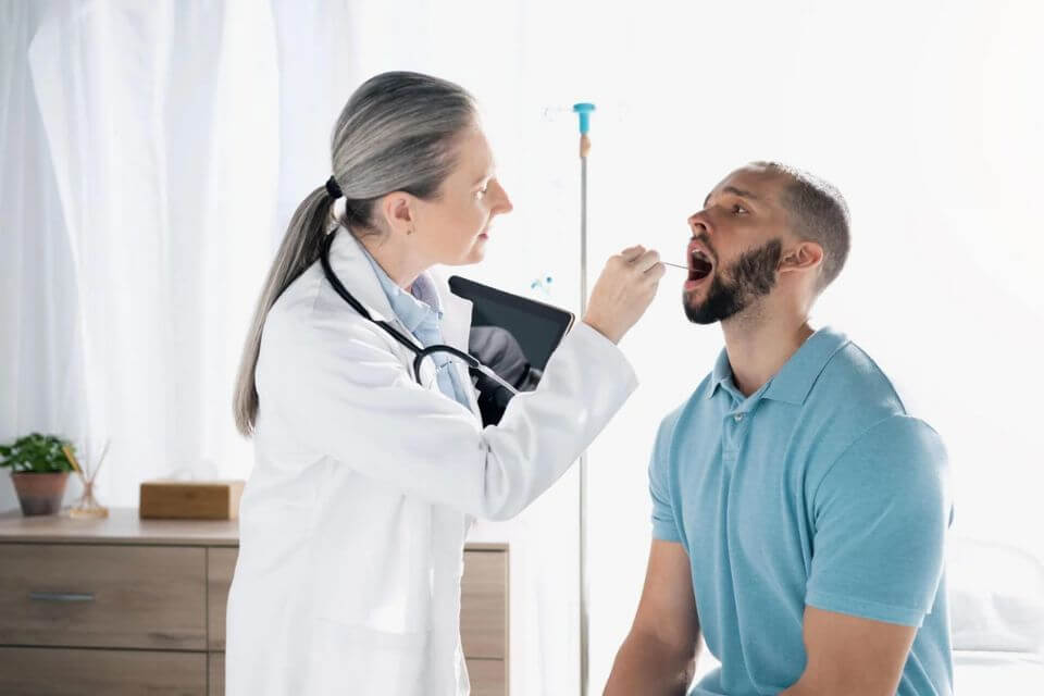 一名女醫(yī)生給男病人進(jìn)行咽拭子采樣