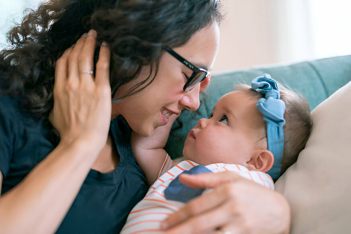 可愛的女嬰依偎在沙發(fā)上，深情地望著媽媽
